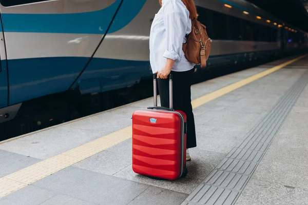 Bavullu kadın istasyona girmek için bekliyor. Tren konseptiyle açık hava macerası.