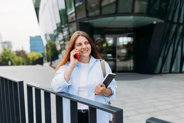 stock image Young redhead businesswoman making phone call over mobile phone in the city. Middle age woman talking on smartphone, walking city urban street at business office center.