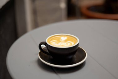 Gri metal masa arkaplanlı bir fincan taze kapuçino. Kahve bağımlılığı konsepti. Sıcak içecek.