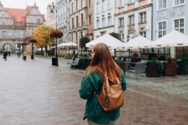 Genç bir turistin arka görüntüsü. Sonbahar gündelik moda tarzı. 30 'lu yaşlarda yalnız bir kadın sokaklarda yürüyor, Avrupa' ya gidiyor.