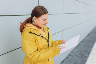 Sarı üniformalı genç bir kadın paketini tutuyor. Teslimat servisi model için beyaz bir paket gönderdi.