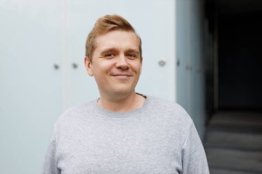 Şehirde sokakta yürüyen yakışıklı bir genç adam. Şehir yaşam tarzı konsepti. Gezgin. Dışarıdaki kameraya günlük kıyafetlerle bakan mutlu bir adamın portresi..