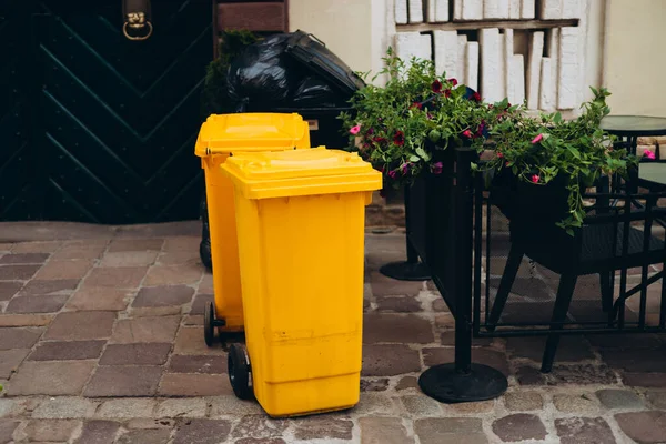Yellow cans out on the street for pick up. Trash recycle. Bin container for disposal garbage waste and save environment. Yellow dustbin for recycle plastic trash
