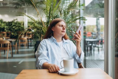 Kızgın kişi masada oturuyor ve kapalı alanda akıllı telefon kullanıyor. Çevrimiçi eğitim, düzen, çalışma veya alışveriş kavramı