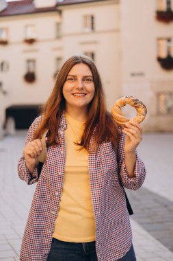 Çekici genç bayan turist, Krakow 'daki pazar meydanında geleneksel Polonya yemeği tutuyor. İlkbaharda Avrupa 'yı geziyorum. Seçici odak.