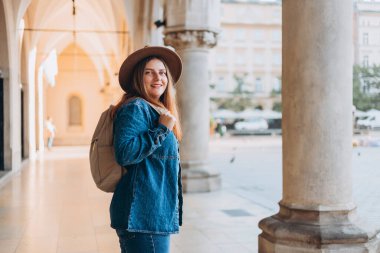 Çekici genç bayan turist yeni şehri keşfediyor. Krakow 'daki Pazar Meydanı' nda poz veren şapkalı kızıl saçlı kız. Sonbaharda Avrupa 'yı geziyorum. Yüksek kalite fotoğraf