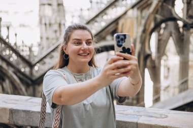 30 'ların güzel kadını Milan Katedrali Duomo di Milano' nun çatısında selfie çekiyor. Yazın Avrupa 'yı geziyorum. Çekici kadın şehri keşfediyor.