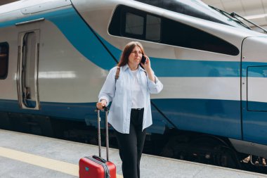 Genç endişeli bayan gezgin tren istasyonunda kayboldu. Telefonda konuşan üzgün kadın hayal kırıklığına uğradı. Kötü haberler duydum. Üzgün kız hoş olmayan bir telefon konuşması yaptı.