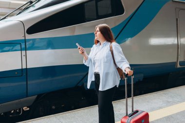 Tren istasyonunda küçük sırt çantalı, 30 'lu yaşlarda tren bekleyen üzgün bir kadın gezgin. Turizm, tek kişilik tatil.