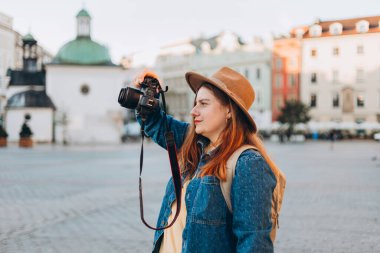 Şapkalı mutlu Avrupalı genç turist Krakow 'daki Pazar Meydanı' nda fotoğraf ya da video çekiyor. Yazın Avrupa 'yı gezmek.