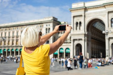 Duomo Meydanı 'nda selfie çeken sarışın güzel bir kadın. Milan, İtalya' daki Galleria Vittorio Emanuele II alışveriş merkezinde. Yazın Avrupa 'yı geziyorum. Çekici kadın şehri keşfediyor.