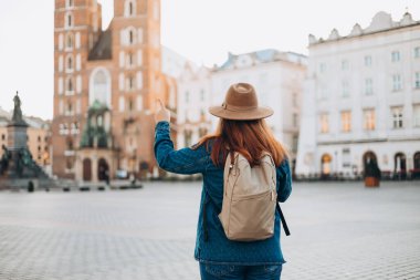 Çekici bayan turist yeni şehri keşfediyor. Kızıl saçlı kadın Krakow 'daki Pazar Meydanı' nı işaret ediyor. Sonbaharda Avrupa 'yı geziyorum. Aziz Mary Bazilikası.