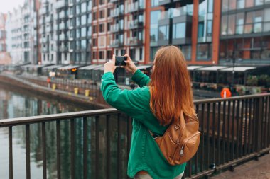 Genç Avrupalı turist, Polonya 'nın Gdansk kentindeki akıllı telefondan fotoğraf veya video çekiyor. Sırt çantalı hippi kız akıllı telefon aletini tut.