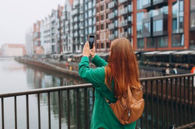 Genç Avrupalı turist, Polonya 'nın Gdansk kentindeki akıllı telefondan fotoğraf veya video çekiyor. Sırt çantalı hippi kız akıllı telefon aletini tut.