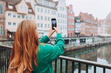 Genç Avrupalı turist, Polonya 'nın Gdansk kentindeki akıllı telefondan fotoğraf veya video çekiyor. Sırt çantalı hippi kız akıllı telefon aletini tut.