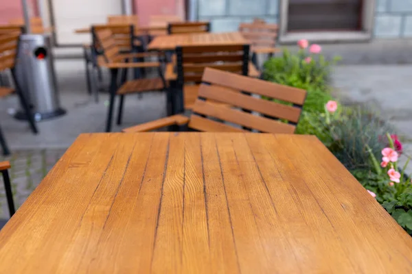 Dining outdoors. Outdoor street cafe tables ready for service. Empty cafe terrace with wooden table and chair. Table of outdoor cafe on sidewalk with colorful flowers