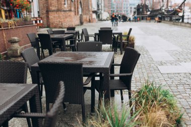 Dışarıda yemek yiyeceğiz. Açık sokak kafe masaları servis için hazır. Masası ve sandalyesi olan boş bir kafe. Kaldırımda bitkilerle dolu bir kafeterya masası.