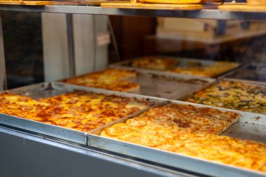 Restoran vitrininde otantik İtalyan pizzası. Cam vitrinli çeşitli pizzacılar. Domatesli pizzaya odaklan.