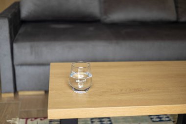 İçerideki ahşap masada bir bardak temiz su. Sabahları sağlıklı olmak için temiz su içmek. Tazeleyici içecek.