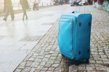 Boş Avrupa caddesinin seyahat bagajı. Turizm, kaldırımlı caddede mavi bavul, yağmurlu hava.