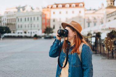 Şapkalı mutlu Avrupalı genç turist Krakow 'daki Pazar Meydanı' nda fotoğraf ya da video çekiyor. Yazın Avrupa 'yı gezmek.