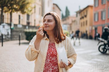 Elinde kremayla dolu Sicilya usulü pasta tutan mutlu kadın. Seyahat, İtalya ve tatil konsepti. Geleneksel lezzetli kek yiyip Avrupa 'yı gezen genç kadınlar.