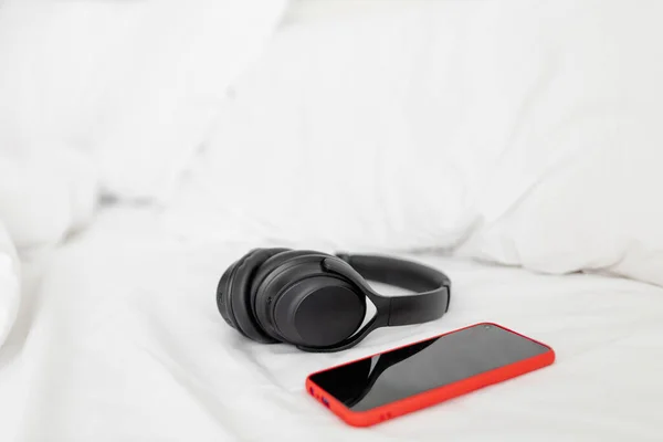 Headphones and smartphone over a bed. Relaxing moment concept.
