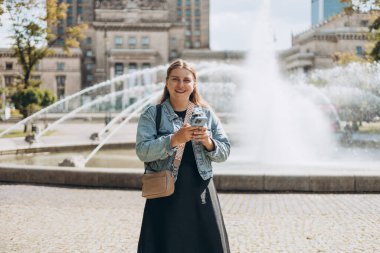 Polonya 'nın Varşova şehrindeki Kültür ve Bilim Sarayı yakınlarındaki parkta yürüyen genç bir turist. Dışarıda dinlenirken cep telefonuyla konuşan bir kadın. Teknoloji, Kentsel yaşam tarzı konsepti