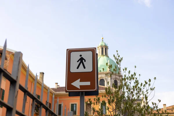 A street sign with an arrow pointing to the left on the city street,