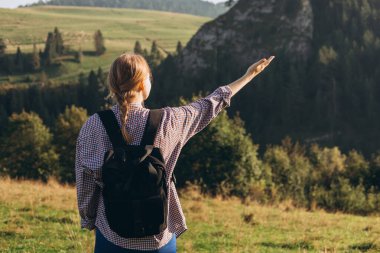 Dağ zirvesinde sırt çantalı, kolları açık bir kadın yürüyüşçü. Seyahat ve aktif yaşam tarzı konsepti. 30 'lu yaşların kızı dağın tepesinden vadi manzarası, açık hava aktiviteleri, arka manzara...