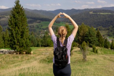 Özgürlük ve aktif yaşam tarzı kavramı. Aşk kalbi şeklinde eller tarafından yapılan maceraperest kadınlar. Aktif yürüyüş kıyafetleri içindeki bir kadının yürüyüş sonrası duruşu..