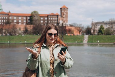 30 'lu yaşlardaki beyaz bir kadın cep telefonu tutuyor ve hoş olmayan mesajlar okuyor. Çok kötü bir haber. Banka tarafından engellenmiş hesabın bozuk akıllı telefon ihbarı