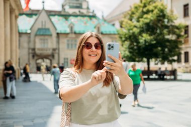 Güzel bir tatilde, eski şehirde yürürken selfie çeken genç bir kızın yakın çekimi..