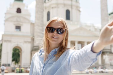 Foto gevşemiş, çekici, pozitif kadın kamerayı tutuyor ve dışarıda şehir merkezinde selfie çekiyor. Hayat tarzı turist tatili konsepti. Bakış açısı.