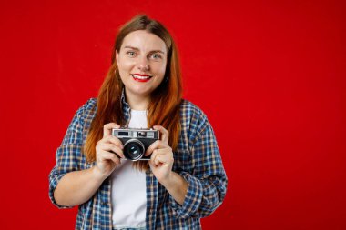 Kırmızı arka planda fotoğraf makinesi olan gülümseyen genç bir kadının portresi.