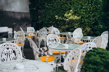 Masaları ve sandalyeleri olan boş bir restoran yaz terası. Restoran masaları açık terasta müşterileri bekliyor..