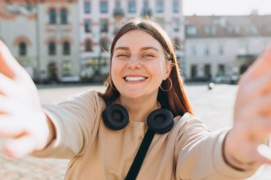 Foto gevşemiş, çekici, pozitif kadın kamerayı tutuyor ve dışarıda şehir merkezinde selfie çekiyor. Yaşam tarzı seyahat tatili konsepti. Bakış açısı.