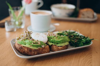 Tost ve haşlanmış yumurta ile yeşil salata ve avokado. Kahvaltı konsepti. Sabah oldu. Avokado yumurtalı sandviç ve tam tahıllı ekmek.