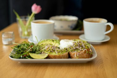 Tost ve haşlanmış yumurta ile yeşil salata ve avokado. Kahvaltı konsepti. Sabah oldu. Avokado yumurtalı sandviç ve tam tahıllı ekmek.