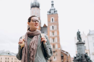 Krakow 'daki Pazar Meydanı' nda Avrupa 'yı sonbaharda gezen mutlu bir turist kadın. Aziz Mary Bazilikası