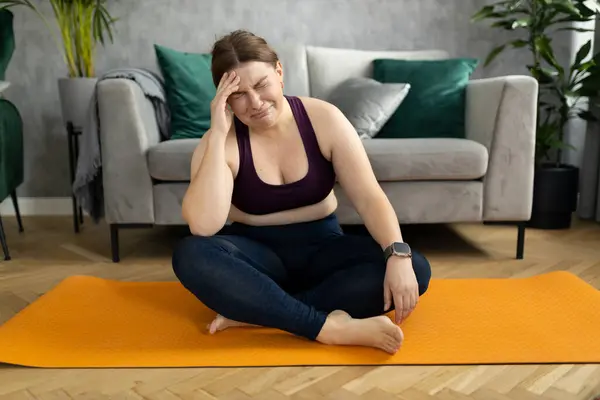 Sad tired fat overweight woman fails to lose weight, can\'t achieve ideal unattainable figure, loses hope. Plus size woman in leggings siting on exercise mat and crying
