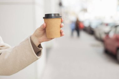 Yemek, dinlenme, paket konsepti. Logoyu kupanın üzerine yerleştir, maket yap. Sokak arka planında kağıt bardak tutan bir kız.