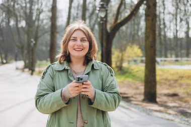 Sıradan giyinmiş 30 'lu yaşlardaki neşeli turist şehir sokaklarında iletişim kurmak için elinde akıllı telefon aleti tutuyor. Mutlu kadın cep telefonuyla konuşuyor ve dışarıda dinleniyor.