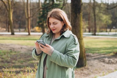 Sıradan giyinmiş 30 'lu yaşlardaki neşeli turist şehir sokaklarında iletişim kurmak için elinde akıllı telefon aleti tutuyor. Mutlu kadın cep telefonuyla konuşuyor ve dışarıda dinleniyor.