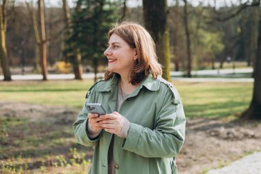 Sıradan giyinmiş 30 'lu yaşlardaki neşeli turist şehir sokaklarında iletişim kurmak için elinde akıllı telefon aleti tutuyor. Mutlu kadın cep telefonuyla konuşuyor ve dışarıda dinleniyor.