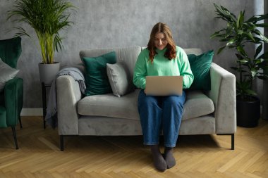 Evdeki kanepede oturan 30 'lu yaşlarda kızıl saçlı güzel bir kadın. Eğitim, iş ve konfor kavramları