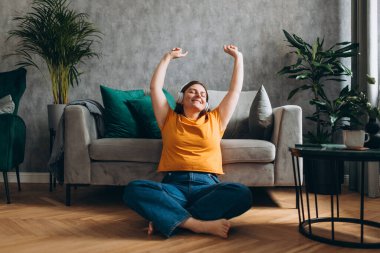 Gülümseyen kız evde dinleniyor, müzik dinliyor, akıllı telefon kullanıyor ve beyaz kulaklık takıyor. Genç kadın evde iyi ses dinlenme odasında eğleniyor.