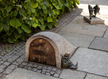 Polonya, Wroclaw 'da bir caddenin zemininde oturan küçük bakır bir goblin heykeli.