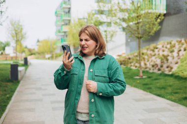 Yaz aylarında sokakta cep telefonu elinde tutan, rahatsız edici ifade ile ekrana bakan, bir hata yaptı ya da metinler ve aramalar rahatsız genç kadın portresi