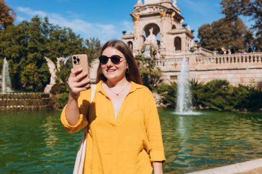 Genç bayan turist Barselona 'daki Ciutadella Parkı' nı ziyaret ediyor. Genç gezgin kadın dışarıda selfie çekiyor. Seyahat, turizm ve tatil kavramı